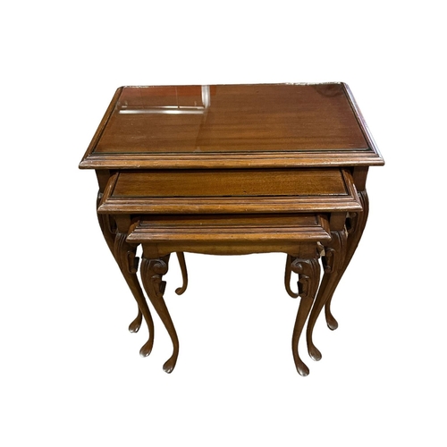 437 - A NEST OF THREE MAHOGANY TABLES each of rectangular outline with glazed inset on carved cabriole leg... 