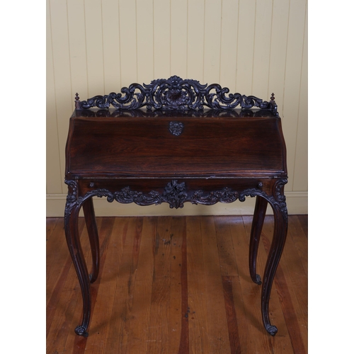 191 - A 19TH CENTURY CONTINENTAL CARVED ROSEWOOD SLOPE FRONT BUREAU the pierced carved gallery above a hin... 