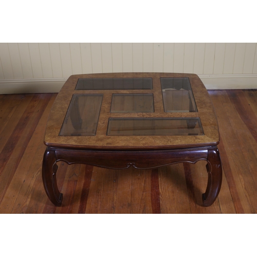 427 - AN ORIENTAL BURR WALNUT STAINED WOOD COFFEE TABLE the shaped top with bevelled glass glazed panels a... 