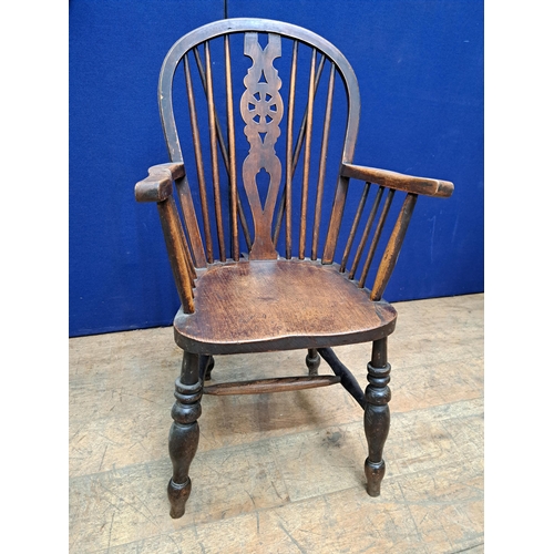 486 - A VINTAGE ELMWOOD WHEEL BACK ELBOW CHAIR with pierced vertical splat and shaped seat on baluster leg... 