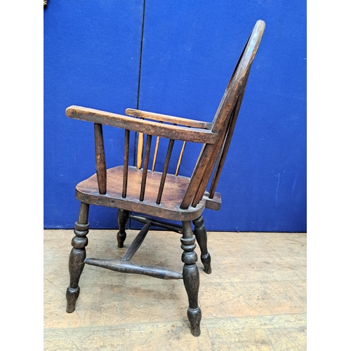 486 - A VINTAGE ELMWOOD WHEEL BACK ELBOW CHAIR with pierced vertical splat and shaped seat on baluster leg... 