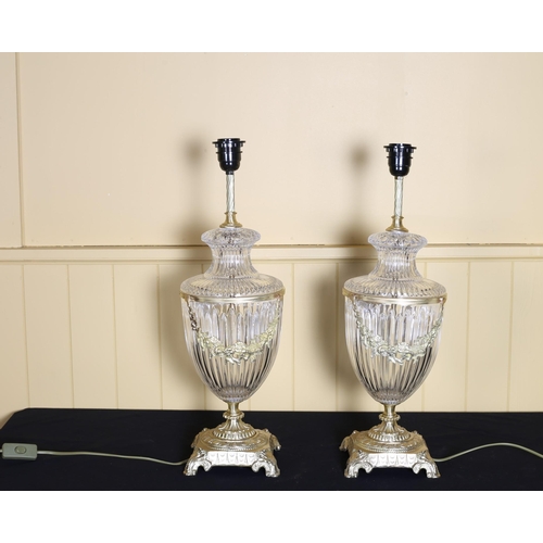 511 - A PAIR OF CLEAR GLASS AND GILT BRASS MOUNTED TABLE LAMPS each of urn form hung with floral festoons ... 