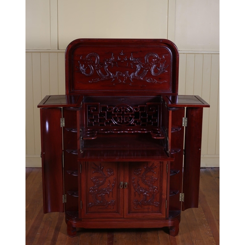 61 - A CHINESE ROSEWOOD COCKTAIL CABINET the hinged lid containing compartments above a pair of cupboards... 