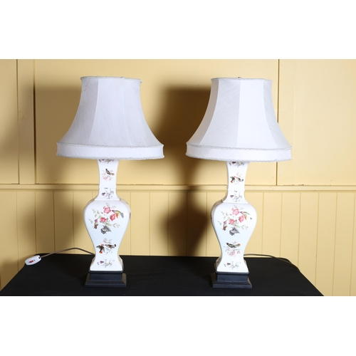 73 - A PAIR OF PORCELAIN TABLE LAMPS the white ground decorated with exotic birds, flowerheads and foliag... 