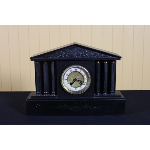 134 - A VINTAGE BLACK MARBLE MANTEL CLOCK of architectural outline the circular dial with brass bezel on p... 