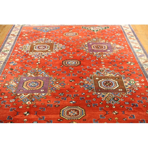 33 - AN ORIENTAL WOOL RUG the red ground with central panel filled with palmettes and hooks within a conf... 