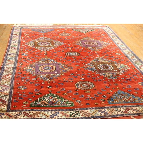 33 - AN ORIENTAL WOOL RUG the red ground with central panel filled with palmettes and hooks within a conf... 