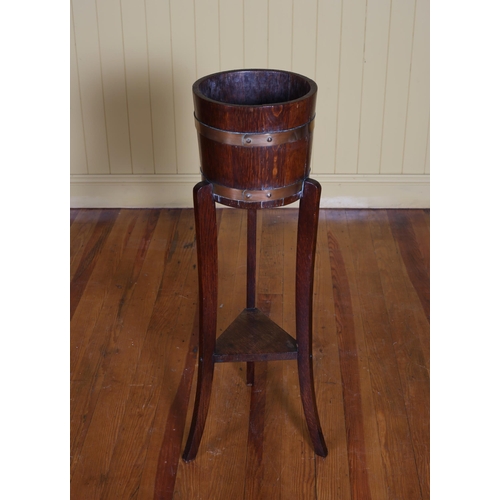 346 - A VINTAGE OAK AND BRASS BOUND JARDINIERE of cylindrical tapering form raised on sabre legs joined by... 