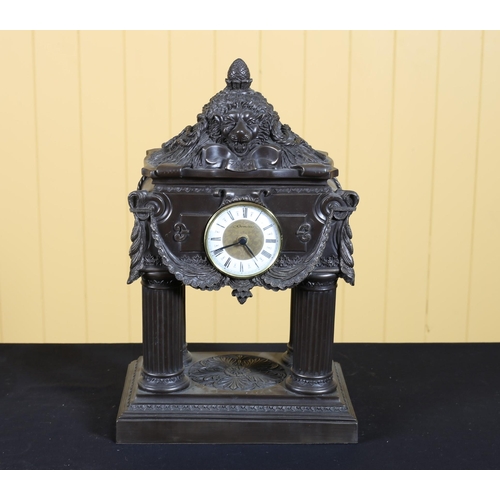 385 - A COLD CAST PORTICO CLOCK surmounted by a lion mask motif raised on four fluted columns and platform... 