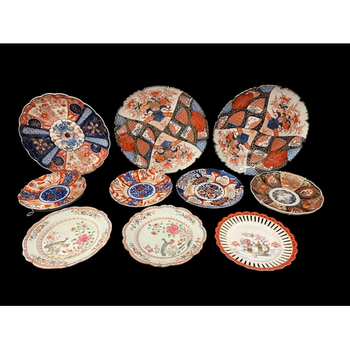 490 - A SET OF THREE IMARI PLATES on stands the white, puce and indigo ground with floral panels with gilt... 