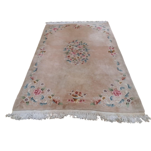 516 - A CHINESE WOOL RUG the fawn ground with central floral panel within a conforming border (stained)