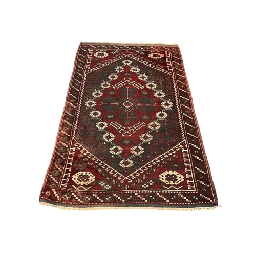 522 - A KAZAK WOOL RUG the wine ground with central panel filled with palmettes, hooks and stylised flower... 