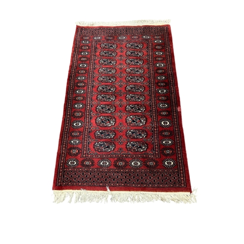 523 - A BOKHARA WOOL RUG the wine ground with central panel filled with palmettes within a conforming bord... 