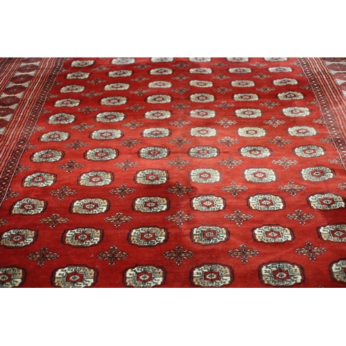 62 - A BOKHARA WOOL RUG the wine ground with central panel filled with palmettes within a conforming bord... 