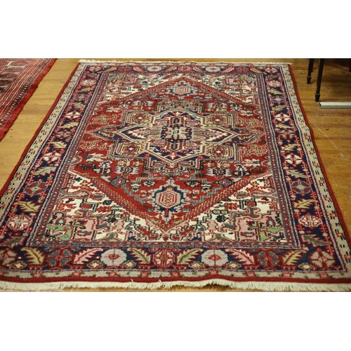 63 - A HERIZ WOOL RUG the multicolour ground with central serrated panels filled with stylised flowerhead... 