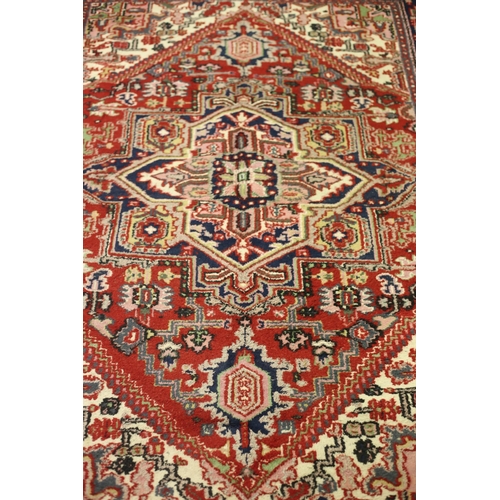 63 - A HERIZ WOOL RUG the multicolour ground with central serrated panels filled with stylised flowerhead... 