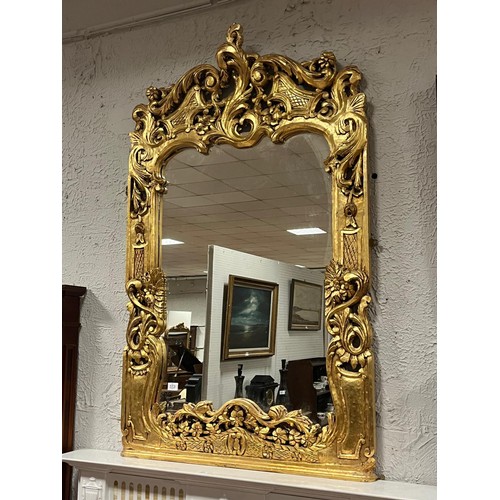 173 - A CONTINENTAL CARVED GILTWOOD MIRROR the shaped plate within a pierced C-scroll flowerhead and folia... 