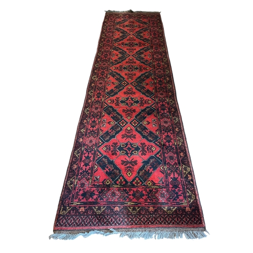 155 - AN AFGHAN WOOL RUNNER the wine and indigo ground with central panel filled with stylised flowerheads... 