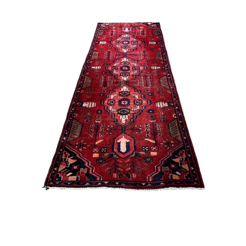 158 - A MIDDLE EASTERN WOOL RUNNER the wine ground with central panel filled with stylised flowerheads and... 