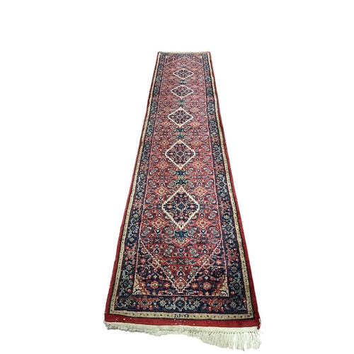 350 - A BIDJAR WOOL RUNNER the wine and indigo ground with central panel filled with stylised flowerheads ... 