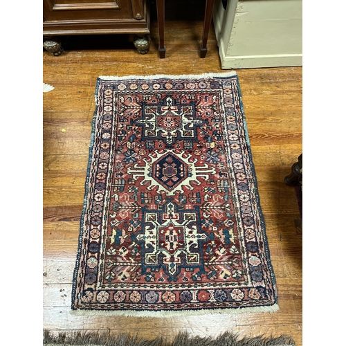 353 - A PERSIAN TRIBAL WOOL RUG the light pink ground with central panel filled with serrated panels and h... 