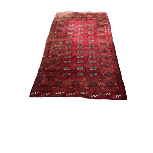 354 - A BOKHARA WOOL RUG the wine ground with central panel filled with palmettes and stylised foliage wit... 