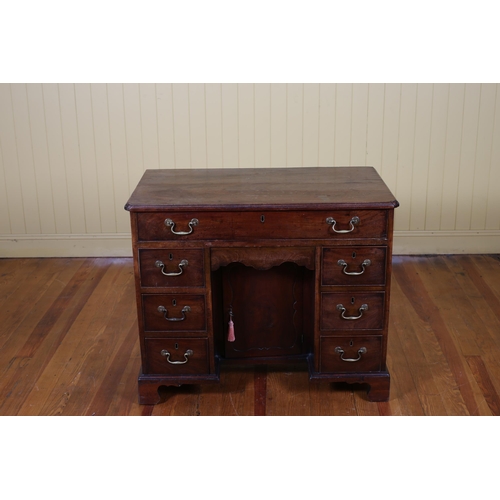 4 - A GEORGIAN MAHOGANY DESK of rectangular outline the shaped top above a frieze drawer centred by a cu... 