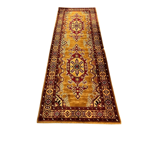 642 - A WOOL RUNNER the gold and wine ground with central panel filled with serrated panels with palmettes... 