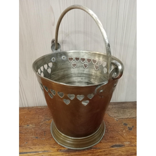 95 - A BRASS SWING HANDLE ICE BUCKET of cylindrical tapering form with heart design rim raised on a circu... 