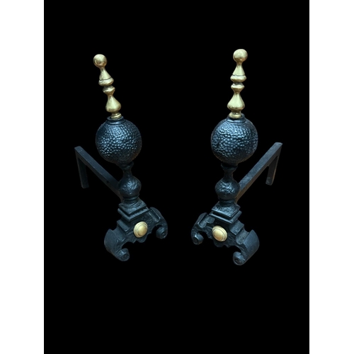 403 - A PAIR OF CAST IRON AND BRASS MOUNTED FIRE DOGS each with a spherical column with brass finial on sc... 