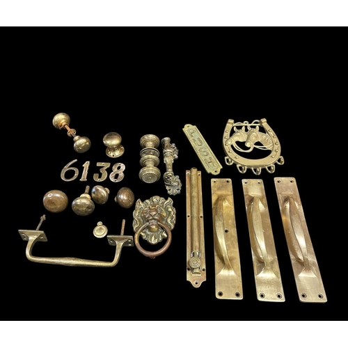 519 - A COLLECTION OF BRASSWARE to include three door pulls, brass door knobs, a brass medusa knocker, a f... 