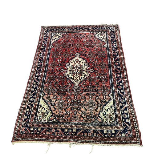 550 - A HAMADAN WOOL RUG the wine, beige and indigo ground with central panel filled with serrated panel, ... 