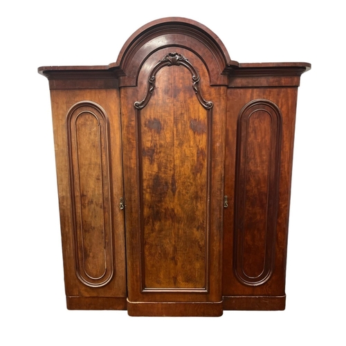 56 - A VICTORIAN MAHOGANY BREAKFRONT WARDROBE the arched pediment above three panel doors with applied de... 