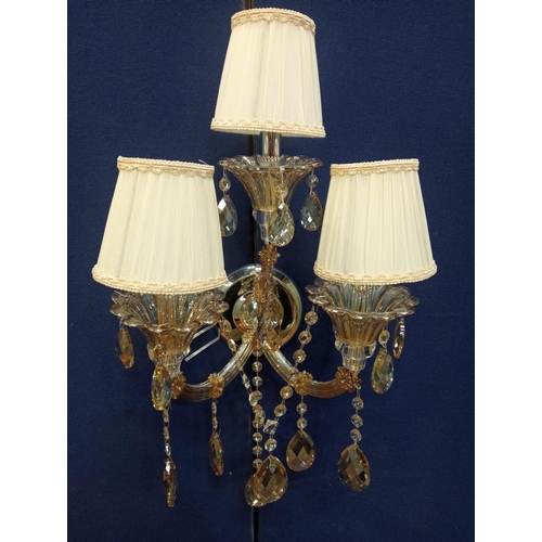 424 - A CHROME AND CUT GLASS THREE BRANCH WALL LIGHT hung with faceted chains and pendant drops with pleat... 