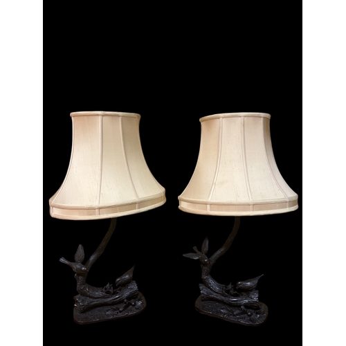 117 - A PAIR OF JEANNE RYNHART COLD CAST FIGURAL TABLE LAMPS each modelled with birds feeding their young ... 