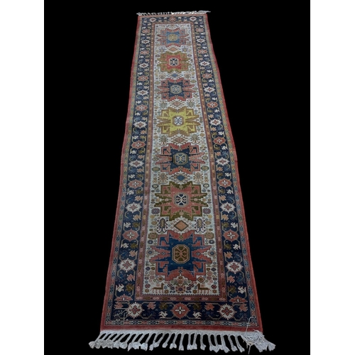 577 - AN ORIENTAL WOOL RUNNER the multicoloured ground with central serrated panels within a conforming bo... 