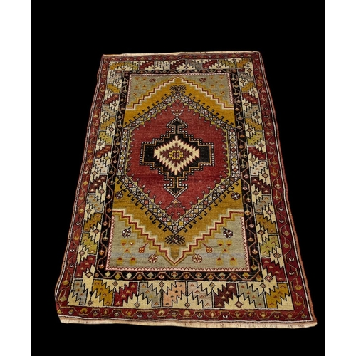 582 - A TURKISH WOOL RUG the multicoloured ground with central serrated panel within a conforming border 1... 