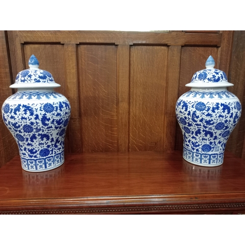 265 - A PAIR OF ORIENTAL BLUE AND WHITE LIDDED URNS each of bulbous form the white ground with stylised fl... 