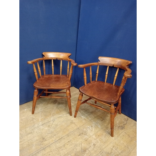 357 - A PAIR OF VINTAGE STAINED ELMWOOD SMOKERS CHAIRS each with a curved top rail with scroll arms and sp... 