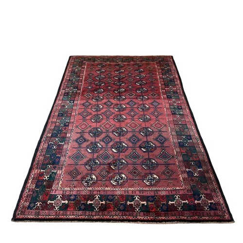 573 - A BOKHARA WOOL RUG the wine ground with octagonal and diamond shaped panels within a conforming bord... 