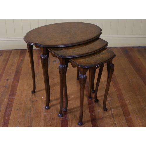 254 - A VINTAGE NEST OF THREE WALNUT TABLES each with a shaped top on carved cabriole legs with pad feet t... 