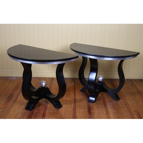 421 - A PAIR OF DESIGNER EBONISED AND SILVERED CONSOLE TABLES each of demi lune outline the shaped tops ra... 