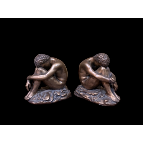 481 - A PAIR OF VINTAGE GILT PLASTER BOOKENDS each modelled as a male shown seated in a crouched position ... 