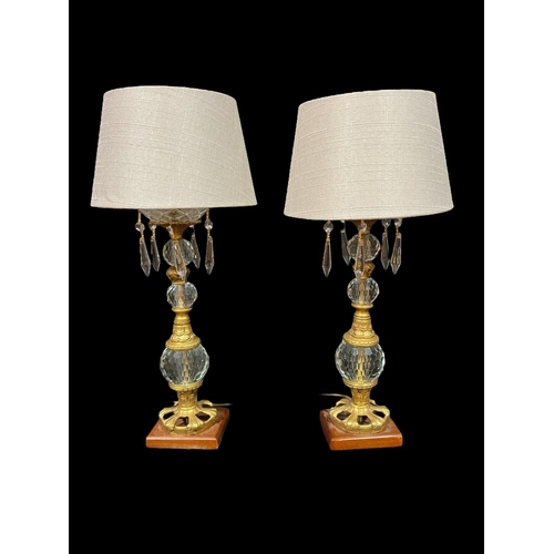 104 - A PAIR OF CONTINENTAL CUT GLASS AND GILT BRASS TABLE LAMPS each with a knopped column hung with face... 