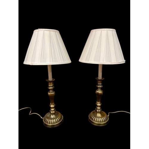 113 - A PAIR OF BRASS TABLE LAMPS each with a faceted column above a circular spreading foot with pleated ... 