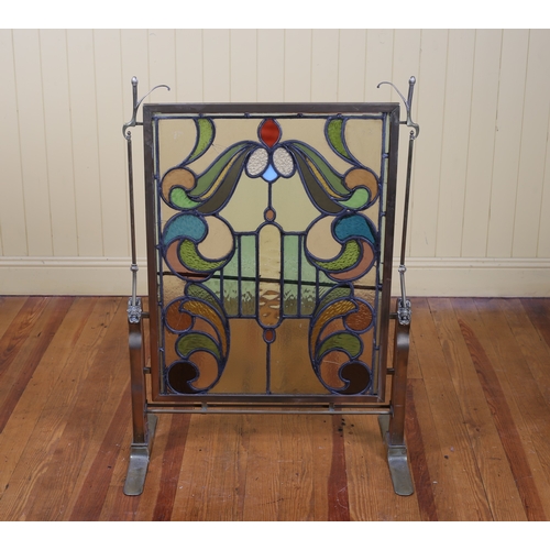 15 - A 19TH CENTURY BRASS AND LEADED GLASS FIRE SCREEN the rectangular multicoloured glass screen on stan... 