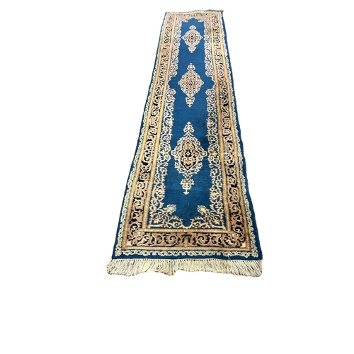 161 - A TURKISH WOOL RUNNER the light blue and beige ground with central scroll shaped panels within a con... 