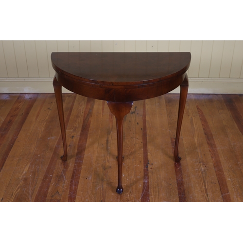 184 - A VINTAGE WALNUT CARD TABLE of demi lune outline the shaped hinged top containing a baize lined inte... 