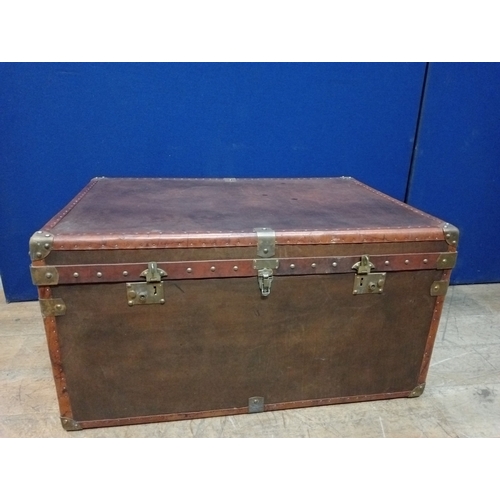 392 - A HIDE UPHOLSTERED AND BRASS BOUND TRUNK of rectangular outline the hinged lid with brass clasps and... 