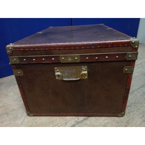 392 - A HIDE UPHOLSTERED AND BRASS BOUND TRUNK of rectangular outline the hinged lid with brass clasps and... 